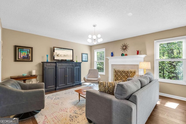 4027 Mount Vernon Dr, Woodstock, GA 30189 - living room featuring wood finished floors, baseboards, a textured ceiling, a chandelier, and a fireplace