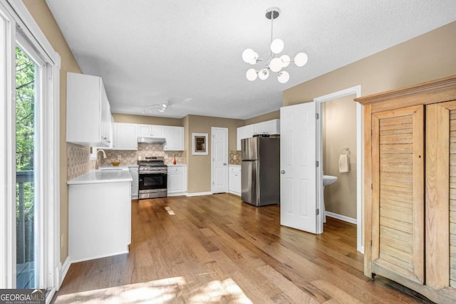 4027 Mount Vernon Dr, Woodstock, GA 30189 - kitchen featuring stainless steel appliances, light countertops, light wood-style flooring, backsplash, and white cabinets