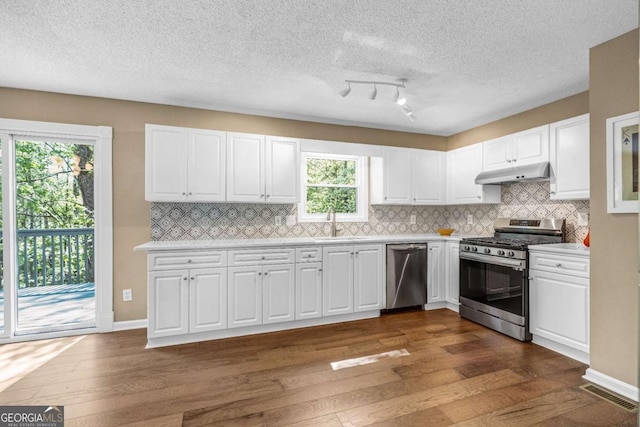 4027 Mount Vernon Dr, Woodstock, GA 30189 - kitchen with appliances with stainless steel finishes, under cabinet range hood, dark wood-style floors, light countertops, and a textured ceiling