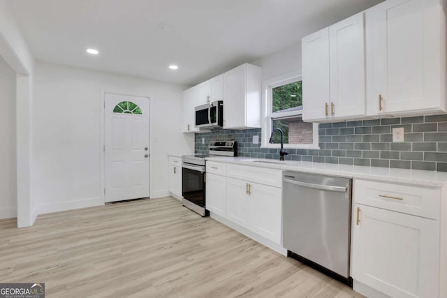 644 Church St NW, Atlanta, GA 30318 - kitchen with appliances with stainless steel finishes, light countertops, decorative backsplash, light wood-style flooring, and white cabinets