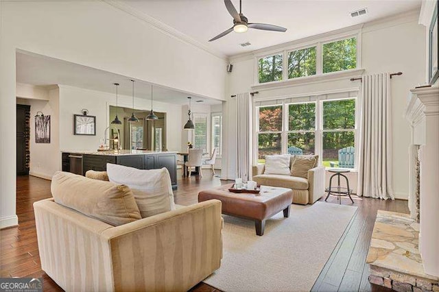 living room with crown molding, a ceiling fan, dark wood-style floors, and a high ceiling