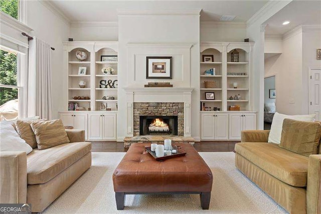 living area with crown molding, a stone fireplace, recessed lighting, and built in shelves