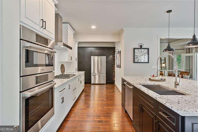 kitchen featuring appliances with stainless steel finishes, a sink, crown molding, dark wood finished floors, and white cabinetry