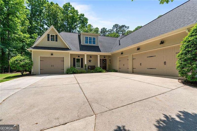 view of front of property with concrete driveway, a garage, and a shingled roof