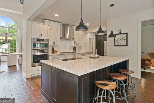 kitchen featuring wall chimney range hood, crown molding, double oven, white cabinetry, and dark wood-style floors