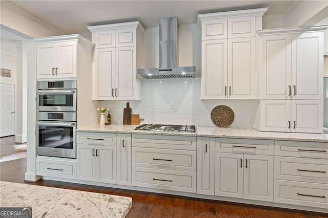 kitchen featuring wall chimney range hood, stainless steel appliances, white cabinets, light stone counters, and dark wood finished floors