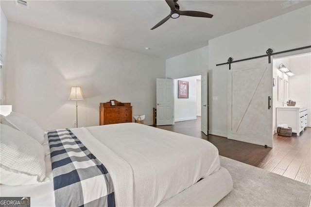 bedroom featuring wood finished floors, a barn door, and ceiling fan
