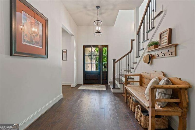 foyer featuring dark wood-style floors, baseboards, stairs, and a chandelier