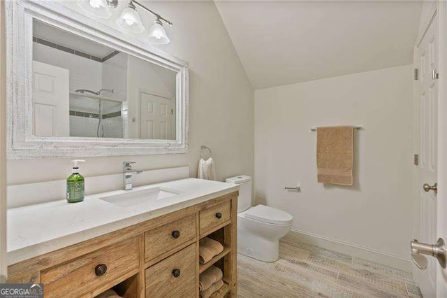 bathroom featuring lofted ceiling, toilet, vanity, wood finished floors, and a shower with door