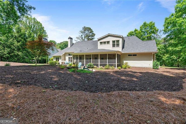 back of property with a sunroom and a chimney
