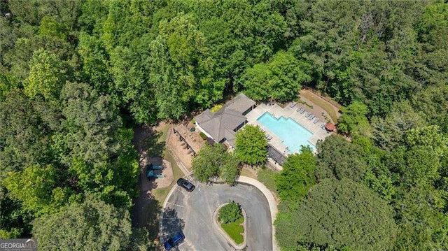 aerial view of property's location featuring a pool and a heavily wooded area