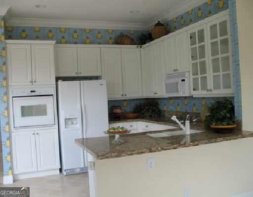 kitchen with white appliances, dark stone counters, glass insert cabinets, a peninsula, and white cabinets