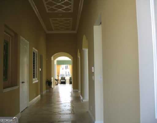 hall featuring arched walkways, baseboards, and crown molding