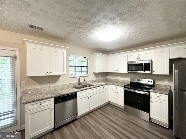3879 Mcgill Ln, Decatur, GA 30034 - kitchen with stainless steel appliances, a sink, dark wood-style floors, a textured ceiling, and white cabinets