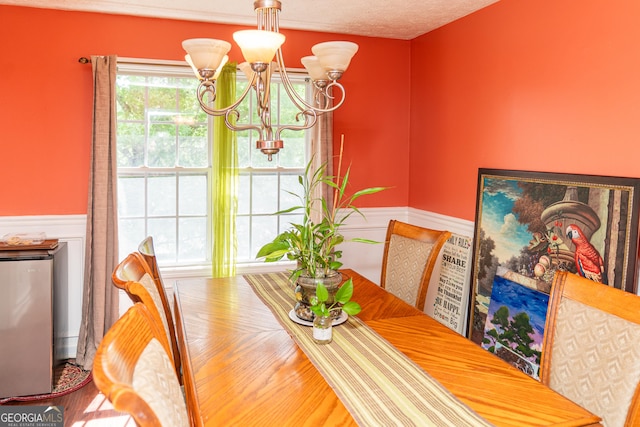 dining room with a chandelier, a wainscoted wall, and wood finished floors
