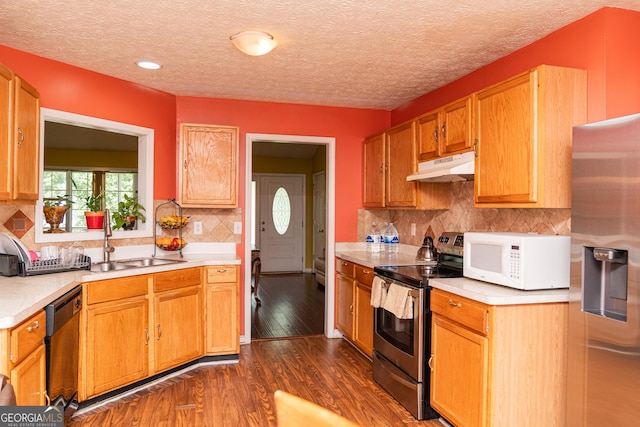 kitchen with appliances with stainless steel finishes, under cabinet range hood, light countertops, dark wood-type flooring, and a textured ceiling