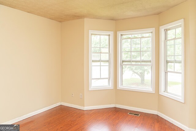 spare room with wood finished floors, baseboards, and a textured ceiling