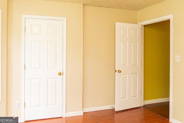 unfurnished bedroom with dark wood finished floors, baseboards, and a textured ceiling