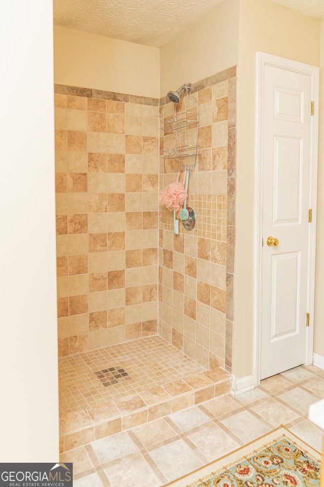 full bathroom with a tile shower, a textured ceiling, and tile patterned floors