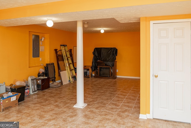 finished basement featuring electric panel and a textured ceiling