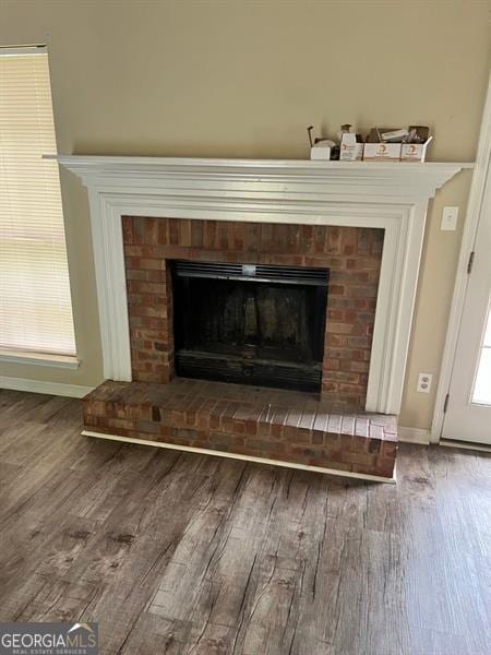 detailed view of wood finished floors, a fireplace, and baseboards