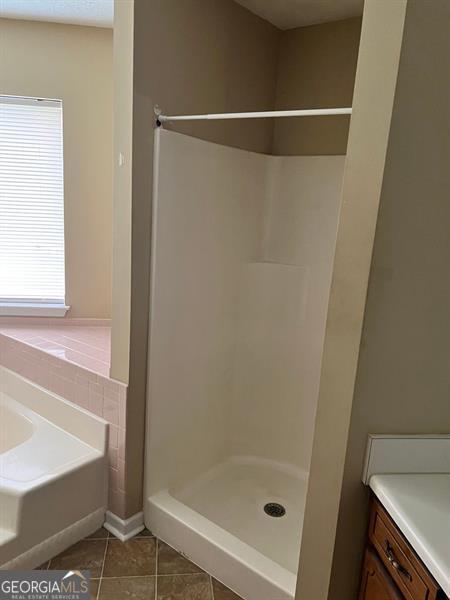full bathroom featuring tile patterned floors, a stall shower, a bath, and vanity