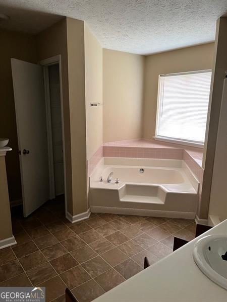 432 Manor Estates Dr, Stockbridge, GA 30281 - bathroom featuring a bath, vanity, a textured ceiling, and tile patterned floors