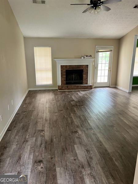 432 Manor Estates Dr, Stockbridge, GA 30281 - unfurnished living room featuring a ceiling fan, dark wood finished floors, and a fireplace