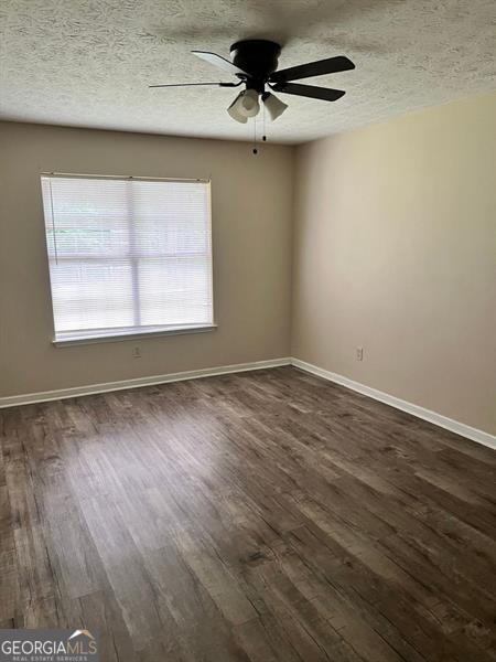 432 Manor Estates Dr, Stockbridge, GA 30281 - spare room with dark wood-type flooring, plenty of natural light, a ceiling fan, and a textured ceiling