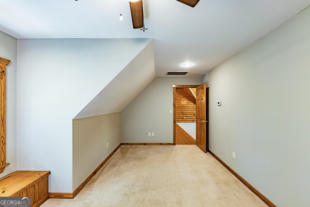 additional living space featuring a ceiling fan, lofted ceiling, baseboards, and light colored carpet