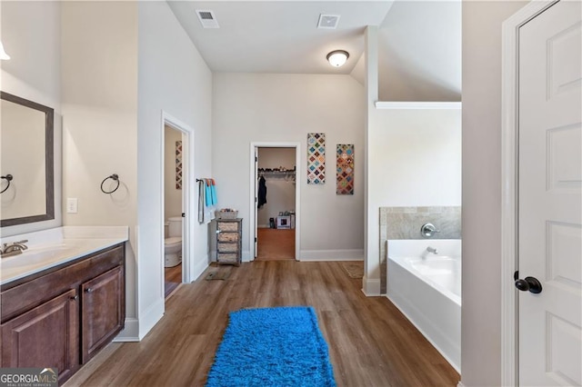 full bath featuring wood finished floors, a bath, baseboards, and vanity