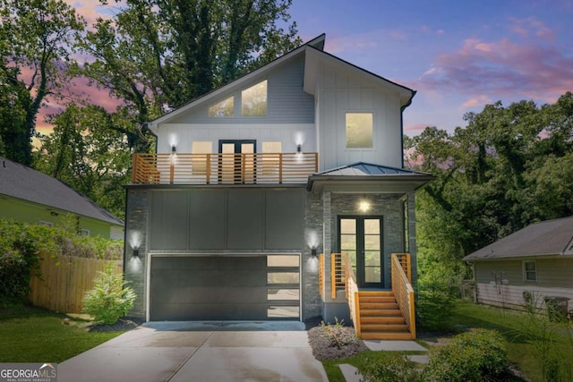 contemporary house featuring a balcony, board and batten siding, concrete driveway, fence, and an attached garage