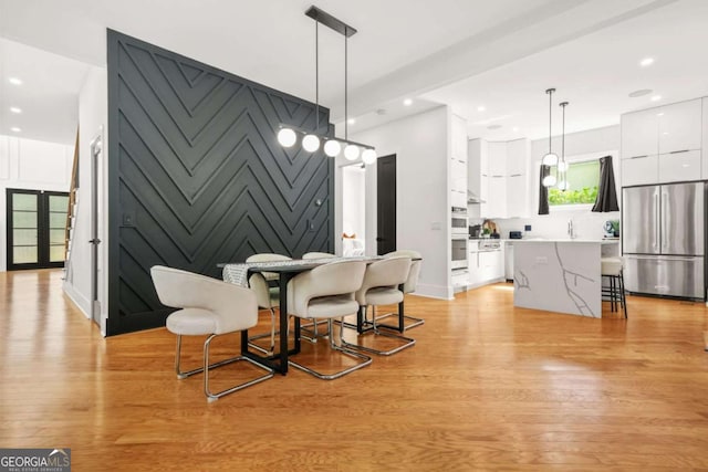 dining space featuring light wood-type flooring, recessed lighting, and a decorative wall