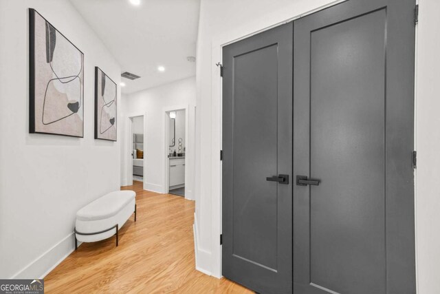 hall with light wood-style flooring, recessed lighting, and baseboards