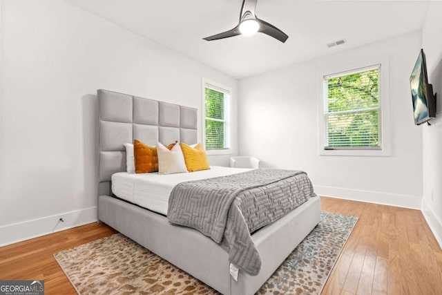 bedroom featuring baseboards, light wood-style floors, and a ceiling fan