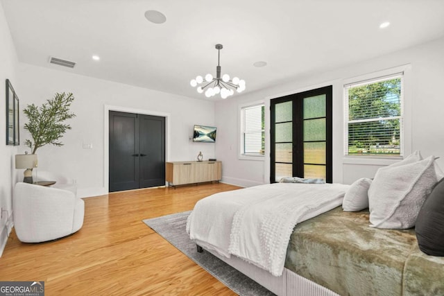bedroom featuring multiple windows, light wood-type flooring, a chandelier, and recessed lighting