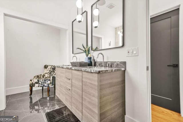 bathroom featuring double vanity, marble finish flooring, and baseboards