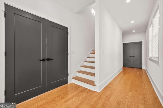 foyer featuring light wood-type flooring, stairs, recessed lighting, and baseboards