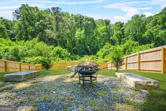 view of yard with an outdoor fire pit and a forest view