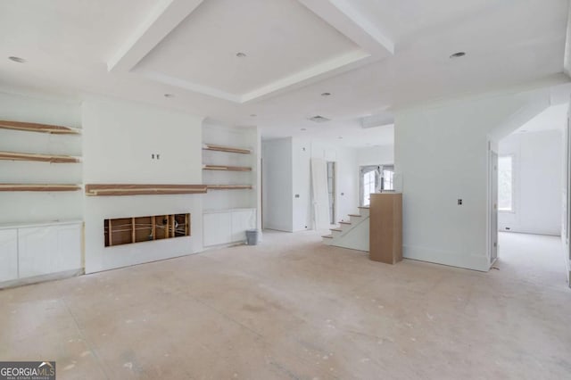 unfurnished living room featuring healthy amount of natural light, a fireplace, and a tray ceiling
