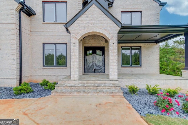 view of exterior entry with brick siding and a porch