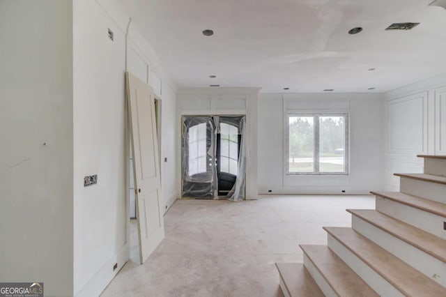 unfurnished living room featuring stairway and baseboards