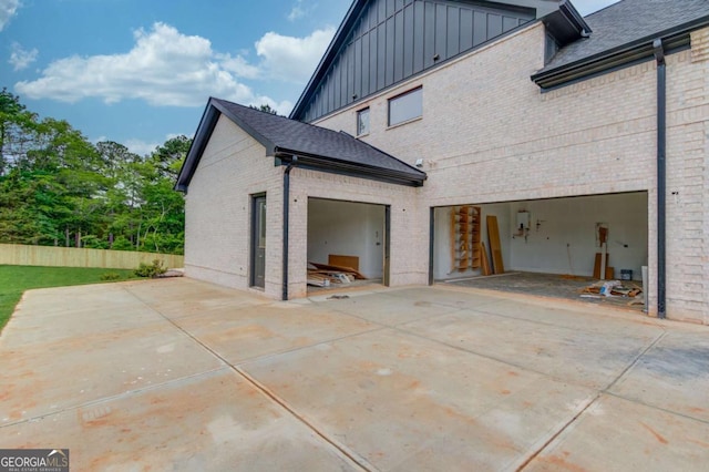 view of home's exterior featuring board and batten siding, brick siding, driveway, fence, and an attached garage