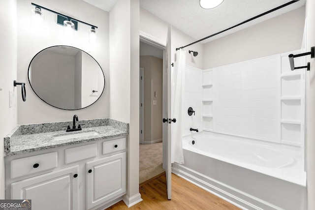 full bath featuring wood finished floors, shower / bath combination with curtain, vanity, and a textured ceiling