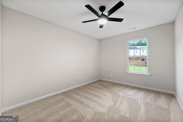 carpeted spare room featuring baseboards, a ceiling fan, and a textured ceiling
