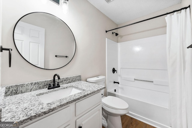 bathroom with toilet, wood finished floors, vanity, a textured ceiling, and shower / tub combo