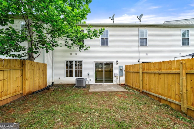 back of house featuring a fenced backyard and central AC