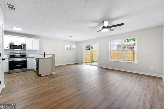 kitchen with stainless steel appliances, a sink, a peninsula, a chandelier, and a ceiling fan