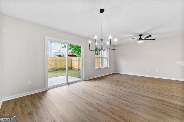unfurnished dining area featuring wood finished floors, a chandelier, baseboards, and ceiling fan