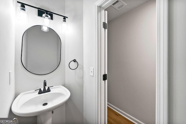 bathroom with a sink, wood finished floors, and baseboards